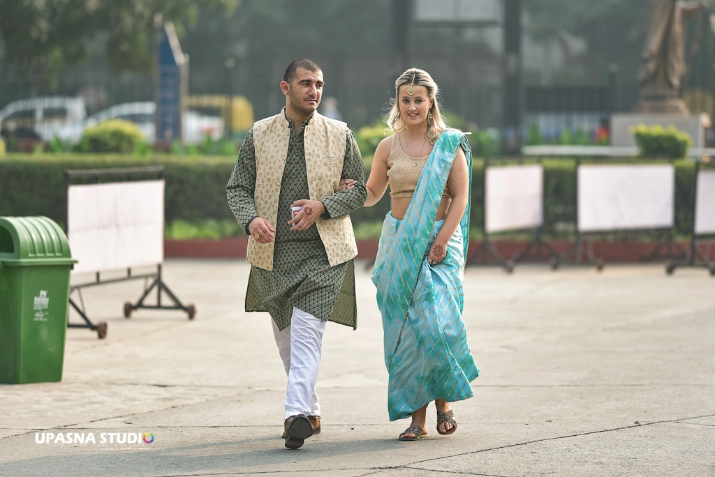A couple in traditional Indian attire walking together, captured by Upasna Studio, a wedding photographer.