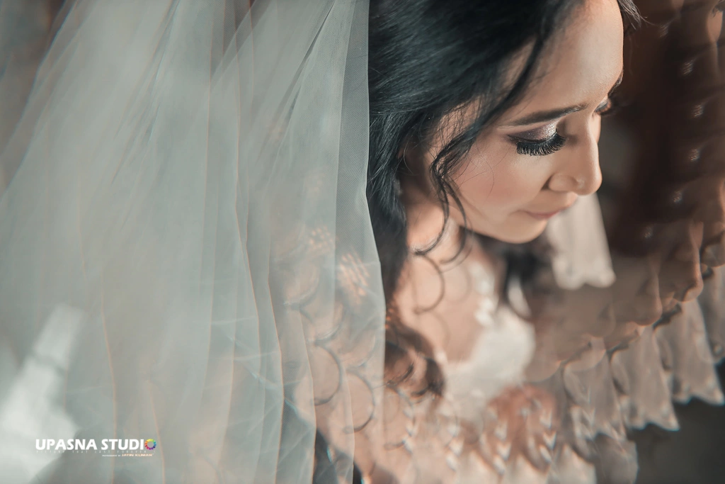 A bride admiring her wedding veil. Captured by Upasna Studio, a candid wedding photographer.