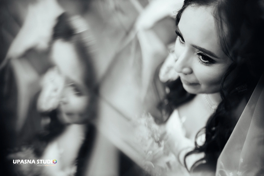 A bride in a wedding dress, gazing at the camera. Captured by Upasna Studio, a candid wedding photographer.