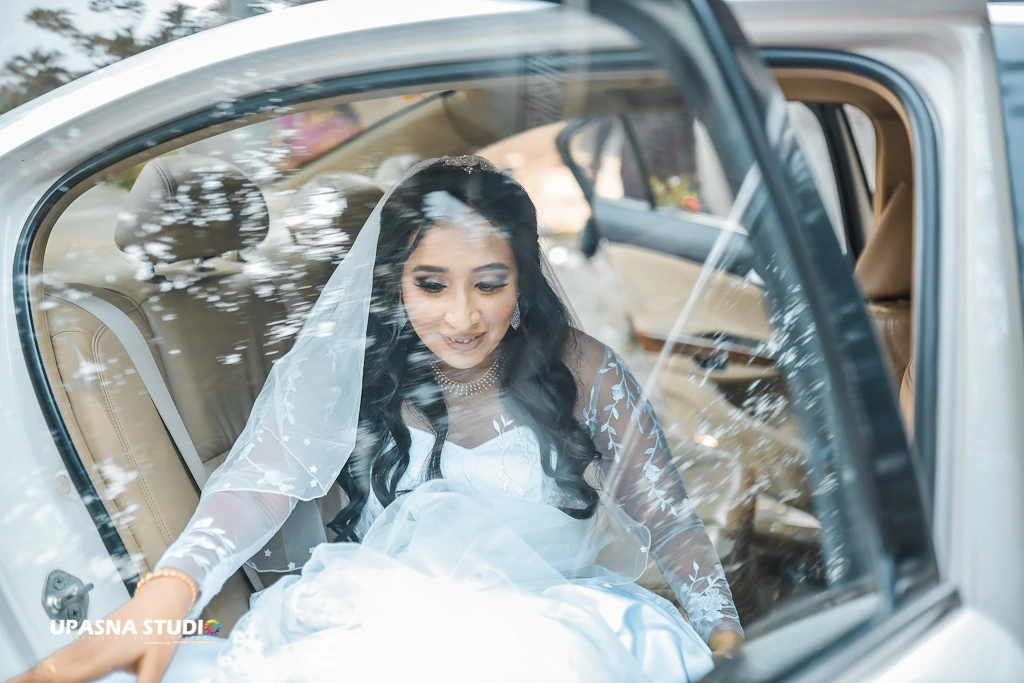 Upasna studio | Wedding photographer in delhi | A bride in a white wedding dress sitting in the back seat of a car, ready to embark on her new journey.