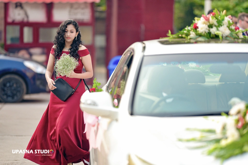 Upasna studio | Wedding photographer in delhi | A woman in a red dress walking towards a car.